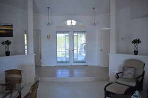 Inside looking at the entry doors to the villa. Tiled open foyer