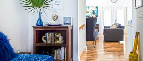 View of nook into the spacious living room. Read, relax, meditate or sleep in your nook with a twin daybed and library with curated local books.