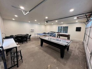 Heated Garage Game Room with Bar, Bar Stools, Seating Area, and Games
