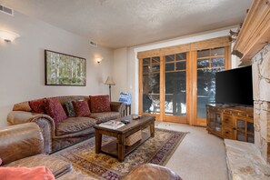 Living Room with plush leather sofas, gas fireplace, 55" LG smart tv, and private hot tub patio access
