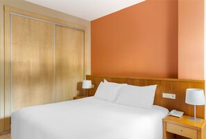 A bedroom with a warm glow, providing a comfortable and minimalist space for a restful night's sleep.