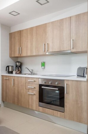 Compact, fully equipped kitchen with wooden cabinetry and modern appliances.