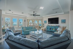 This open-concept living room blends modern comfort with coastal style, featuring soft blue tones.