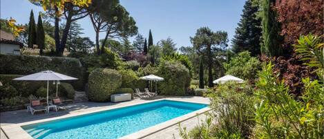 Piscine avec transats, parasols, pool-house et douche