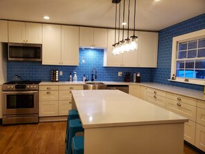 The new kitchen with island and blue subway tile