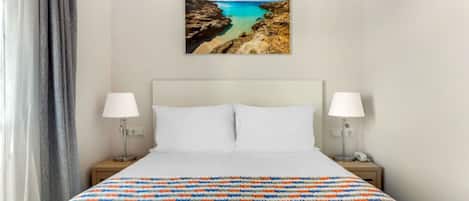 Minimalist bedroom with vibrant bedding and artful decor for a peaceful rest.