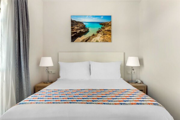 Minimalist bedroom with vibrant bedding and artful decor for a peaceful rest.