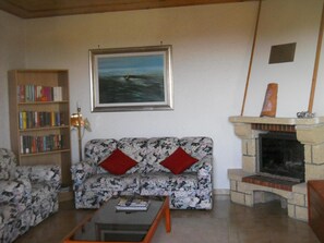a  corner from living room with fireplace ,library and comfortable sofa and armchairs