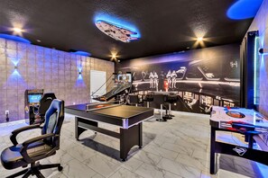 Enter a galaxy of fun in this epic game room with a space-themed mural and neon lighting - Equipped with a gaming chair, ping-pong table and arcade setup for hours of entertainment - An immersive experience that’s out of this world