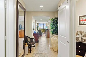 Entering the apartment from the hallway, the bunk and laundry rooms are tucked off to the side, followed by the primary suite to the left and then the open plan living space.