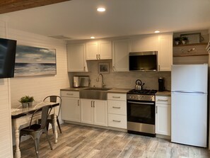 Kitchen is well equipped with farmhouse sink, oven/stove, microwave, & fridge