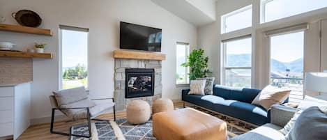The living room, freshly appointed with comfy furniture, a smart TV and fireplace, offers easy access to the outdoor deck and spectacular views.