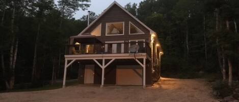 Front of the cottage at evening with outdoor lighting. 