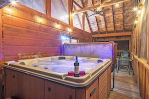 Hot tub with string lighting on screened in porch.