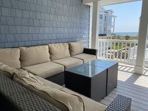 Ocean view from second floor covered deck with large L-shaped sofa.