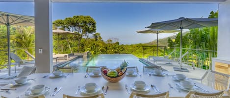 Outdoor dining facing the pool and mountain and beach views