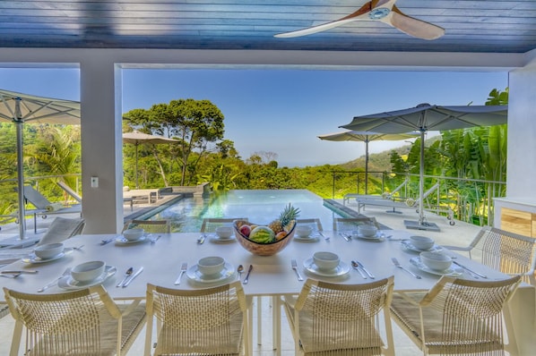 Outdoor dining facing the pool and mountain and beach views