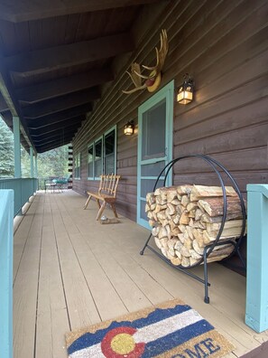 Large front porch with swing, 4-person outside dining space and wooden bench.