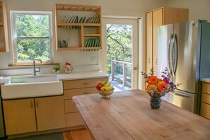 Across island to farm sink, deck door, pull-out pantry. Photo: Lynn Christoffers