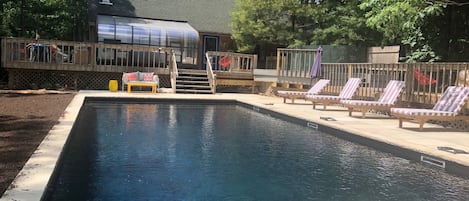 View of brand new heated pool with sandstone patio, pool loungers, and house
