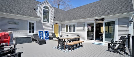 Large deck with patio table and ample seating | Yellow door is the entrance to the home
