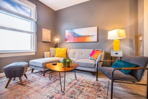 This spacious living room features a plush, modern sofa that serves as the centerpiece, inviting relaxation and comfort. With soft cushions and a sleek, stylish design, the sofa complements the minimalist decor, creating a warm and inviting atmosphere
