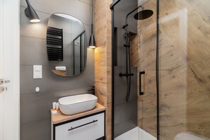 A bathroom showcasing a sleek shower with glass doors, beige tiles, and modern fixtures.