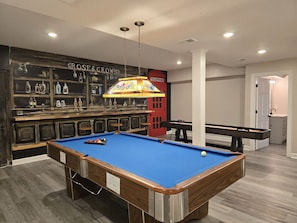 Games room with a bar backdrop mural, pool table and shuffle board table