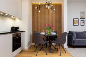 The living area features a sleek dining table and a flat-screen television.