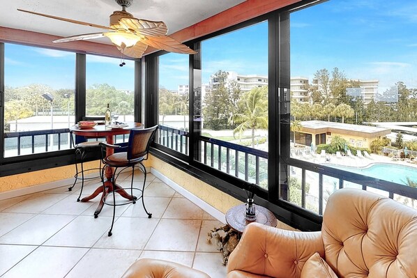 Great wall of windows shows off the pool and tennis courts....love those palm trees!