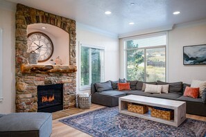 Experience the cozy living room, outfitted with plush seating, an expansive smart TV, and sliding patio doors that frame the breathtaking mountain vistas.