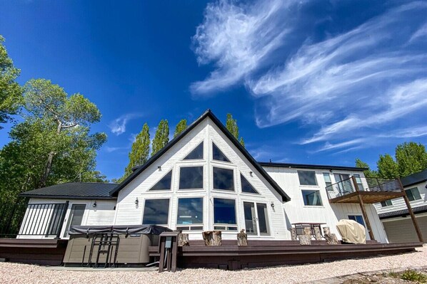 Modern mountain retreat with expansive windows, hot tub, and sunny deck—perfect for relaxing or entertaining.