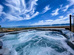Soak in the bubbly hot tub with breathtaking lake views under a stunning sky.