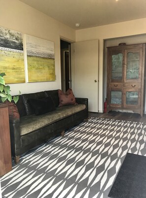 Comfy midcentury couch, armoire with dishes, and original art by host. 
