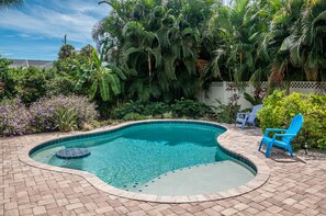 Private heated pool with tanning shelf surrounded by tropical landscape