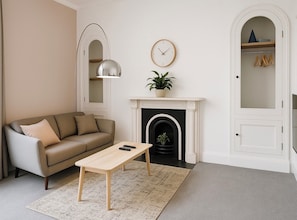 Bright, stylish living room with a comfy grey sofa, modern decor, and a charming fireplace. Perfect for relaxing evenings with a warm, inviting ambiance. The perfect blend of comfort and character for your stay!