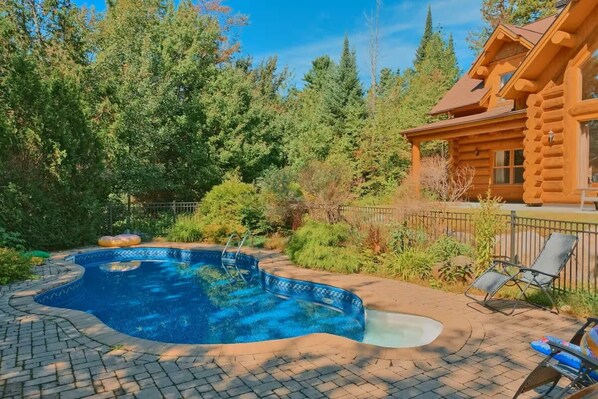 Private pool surrounded by lush greenery and stone patio seating