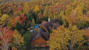 Aerial view showing the log cabin nestled within vibrant fall foliage