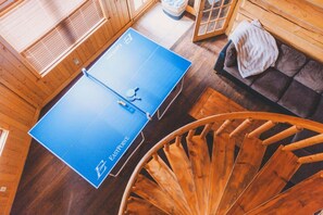 Ping pong table and seating area next to a spiral wooden staircase