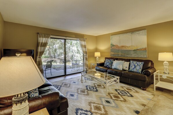 Living Room - This large living space has a comfortable seating with a big screen TV for your viewing enjoyment.  This ground floor unit has sliding doors to the patio and landscaped grounds.