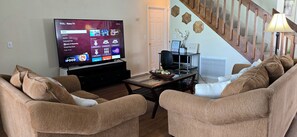 Living room with  comfortable couches, a 75-inch smart tv, and working desk.