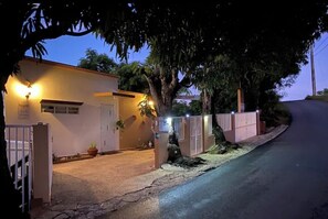 Unique designed from of home at sunset. Mango trees cut thru secured fence 