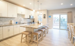 UNIT A (4Bdrm):  The kitchen showcases professional-grade appliances, seamlessly connecting to the living room and offering ample space for food preparation.

Dining table for 6 guests, plus bar stools at the nearby kitchen island.
