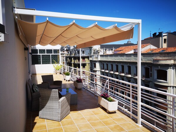 Terraza con pérgola, sofás y mesa. / Terrace with pergola, sofas and table.