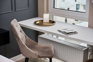 A functional workspace with a comfortable beige chair and desk, placed near a window for natural lighting. The design blends utility with elegance.