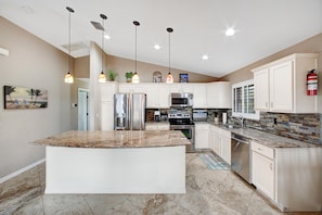 Open-concept kitchen with granite countertops, stainless steel appliances and fully equipped with cooking utensils. Island has two seats which are not shown in photos.