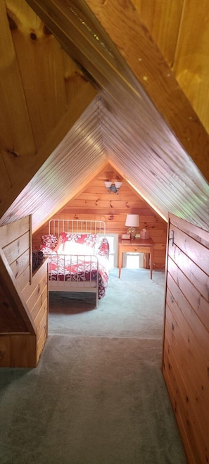 Twin size bed in an alcove with a skylight wndowi