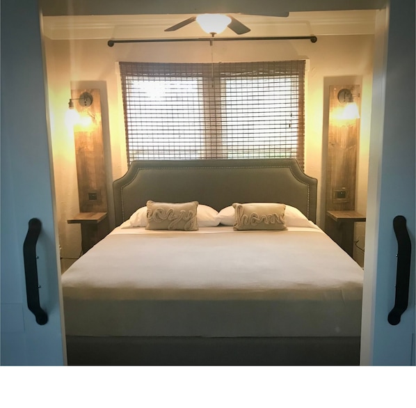 Bedroom boasts king memory foam bed with ceiling fan, separate window AC unit and open closet with hangers