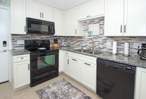 New kitchen cabinets with quartz countertops, glass tile backsplash.