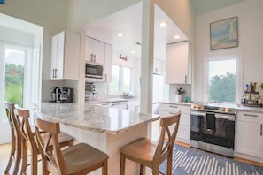 The beautifully renovated kitchen features granite counters, white cabinets and stainless steel appliances.